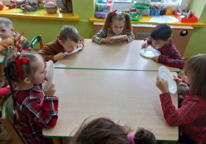 Dzieci przy stoliku zlizują miód z talerzy