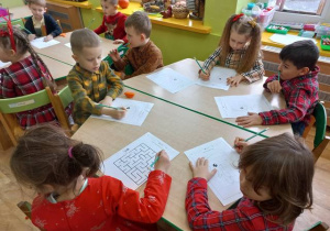 Dzieci siedzą przy stoliku i rysują misie