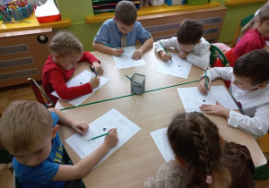 Dzieci siedzą przy stoliku i rysują misie