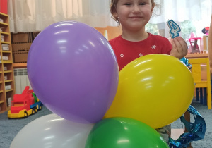 Ania trzyma w ręku urodzinowe balony.