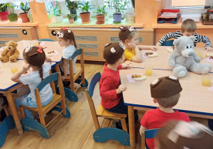 Misiowe przyjęcie- dzieci siedzą przy stolikach i delektują się słodkościami przygotowanymi przez rodziców.