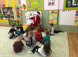 Dzieci siedzą na dywanie Mikołaj czyta świąteczne opowiadanie.