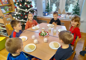Dzieci siedzą przy stole, jedzą mikołajkowe śniadanie.