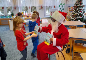 Mikołaj rozdaje dzieciom książki.