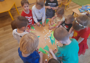 Dzieci wykonują zakładkę – naklejają bombki i gwiazdki na choinkę.