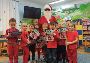 Dzieci trzymają książki, które dostały od Mikołaja.