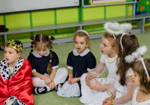 Aniołki i dzieci siedzą na dywanie