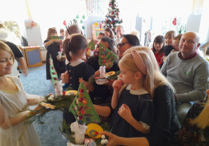 Dzieci wręczają rodzicom świąteczne stroiki.