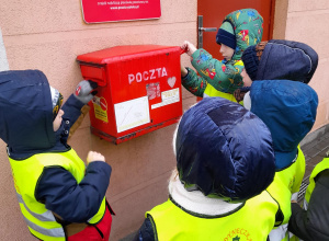 Dzieci wrzucają kartki do skrzynki pocztowej.