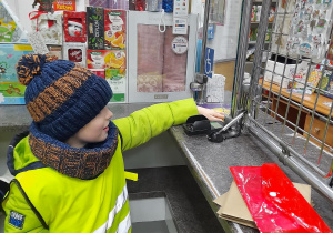 Chłopiec podczas wycieczki na pocztę kupuje znaczki.