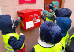 Dzieci wrzucają kartki do skrzynki pocztowej.