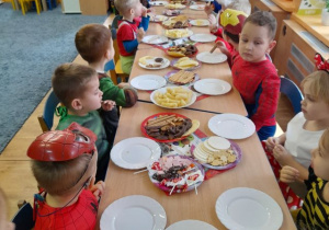 Dzieci częstują się słodyczami przy stoliku.
