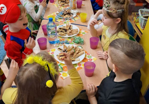 Dzieci częstują się słodyczami przy stoliku.