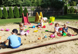 Grupa dzieci bawiących się w piaskownicy.