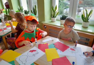 Dzieci przy stolikach wykonują wydzieranki z papieru.