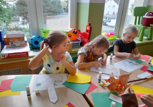 Dzieci przy stolikach wykonują wydzieranki z papieru.