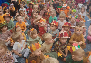 Dzieci bawią się na widowni podczas jesiennego koncertu, wszystkie w jesiennych przebraniach.