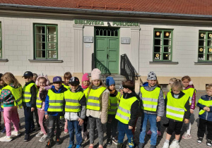 Dzieci w żółtych kamizelkach pod Biblioteką Miejską.