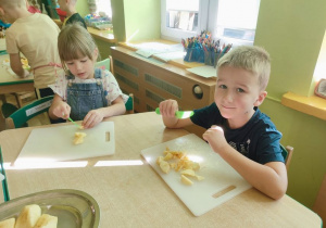 Dwoje dzieci kroi jabłka na deskach do krojenia
