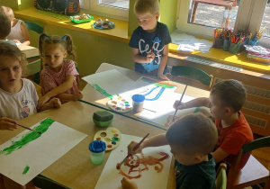 Dzieci przy stoliku malują farbami