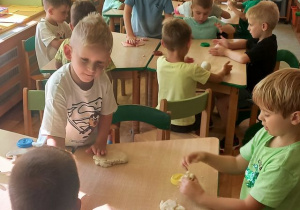 Grupa dzieci przy stolikach lepi z masy solnej