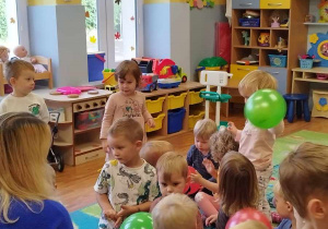 Pani logopedka prezentuje dzieciom ćwiczenie z balonikiem.