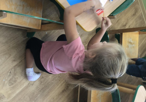 Dziewczynka wykonuje domek z papieru.