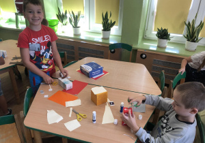 Dzieci przy stolikach tworzą budynki do makiety.