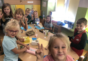 Dzieci przy stolikach tworzą budynki do makiety.