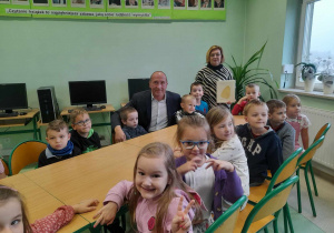 Dyrektor szkoły i pani bibliotekarka pozują wraz z dziećmi do zdjęcia.