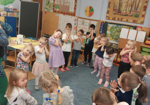 Dzieci podczas zajęć na dywanie naśladują ruchy nauczycielki.