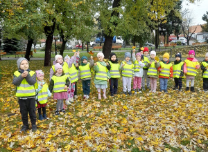 Dzieci stoją w parku trzymając kolorowe listki.