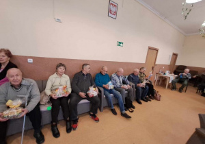 Seniorzy siedzący z paczkami od przedszkolaków