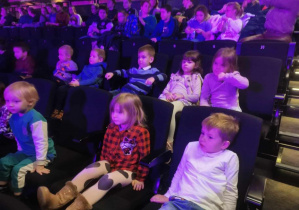 Grupa dzieci siedzi w teatrze.