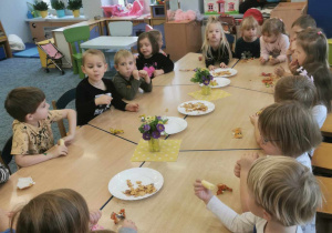 Grupa dzieci przy stolikach podczas słodkiego poczęstunku.