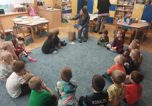 Dzieci słuchające nauczycielki czytającej książkę.