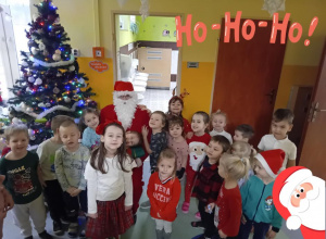 Dzieci stoją z Mikołajem w korytarzu przedszkola