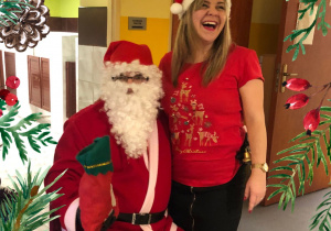 Uśmiechnięta nauczycielka pozuje ze św. Mikołajem.