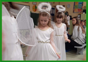 Dziewczynki w strojach aniołów wchodzą do sali przedszkolnej.