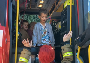 Dzieci wsiadają do wozu strażackiego
