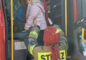 Dzieci wysiadają z wozu strażackiego