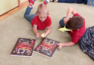 Chłopcy leżą na dywanie i oglądają książki