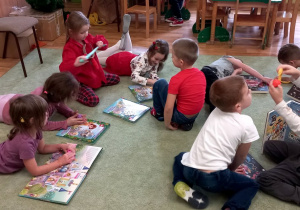 Dzieci oglądają książki na dywanie