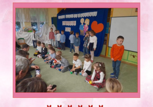 Zdjęcie w różowej ramce przedstawiające dzieci podczas gry na kolorowych dzwoneczkach.