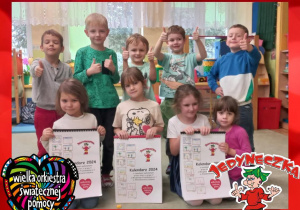Dzieci z grupy V dumnie prezentujące wykonane przez siebie kalendarze na licytację Wielkiej Orkiestry Świątecznej Pomocy.