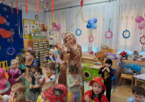 Dzieci w przebraniach i nauczycielka w stroju królowej podczas zabawy na balu.