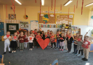 Grupa dzieci trzymająca czerwone serduszka.
