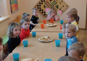 Dzieci przy stoliku podczas słodkiego poczęstunku.