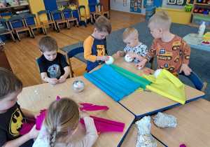 Dzieci wykorzystując różnorodny materiał plastyczny ozdabiają styropianowe kule wg. własnej inwencji twórczej.