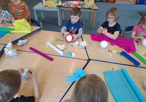 Dzieci wykorzystując różnorodny materiał plastyczny ozdabiają styropianowe kule wg. własnej inwencji twórczej.
